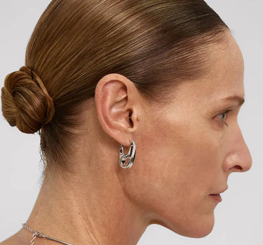 Woman wearing Contour Silver Hoops Earrings, showcasing minimalist sculptural design with smooth curves.