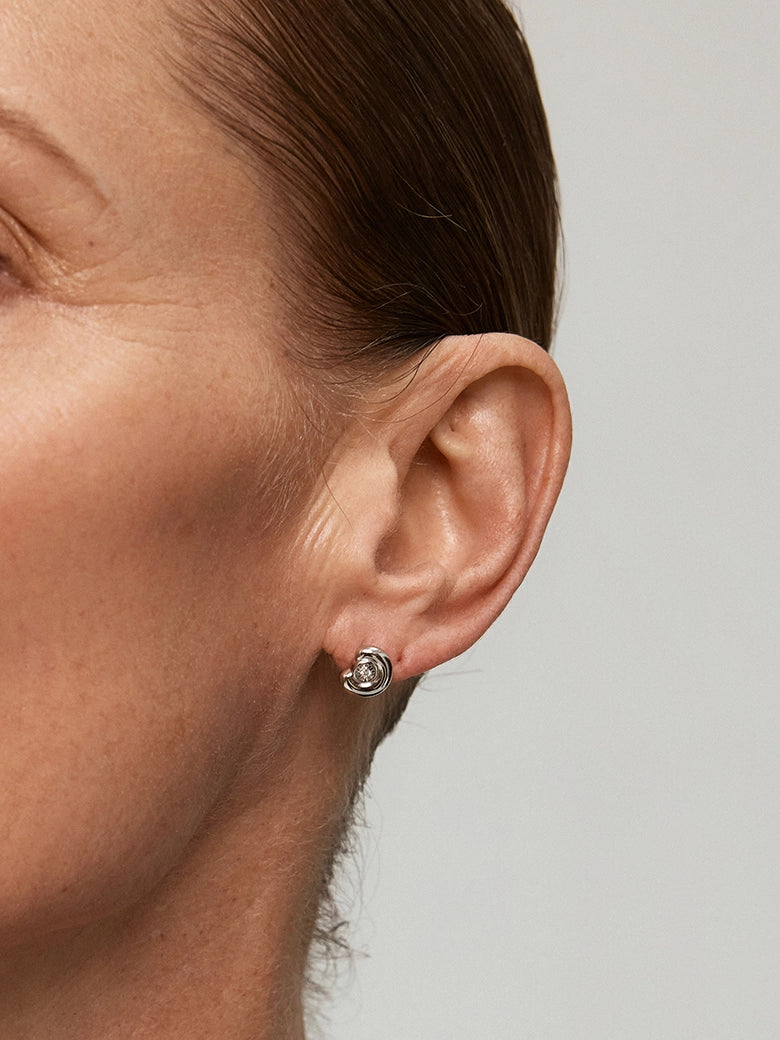 Close-up of Diamond Arc Silver Stud Earrings worn on a model's ear, showcasing their elegant design.