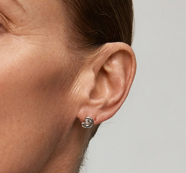 Close-up of Diamond Arc Silver Stud Earrings worn on a model's ear, showcasing their elegant design.