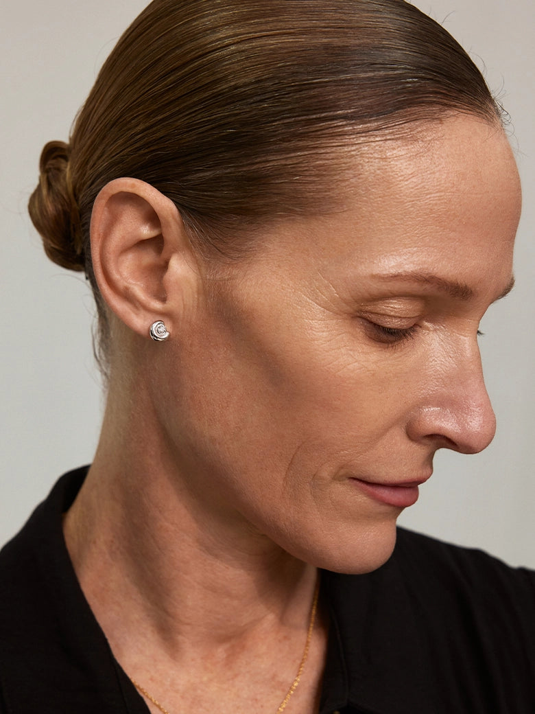 Model wearing Diamond Arc Silver Stud Earrings, showcasing elegant design and diamond accents in a close-up profile view.
