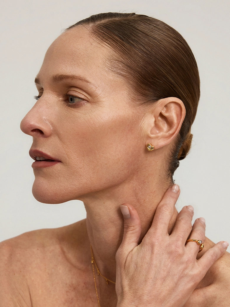 Close-up of a model showcasing Diamond Arc Stud Earrings and gold rings, highlighting minimalist elegance.