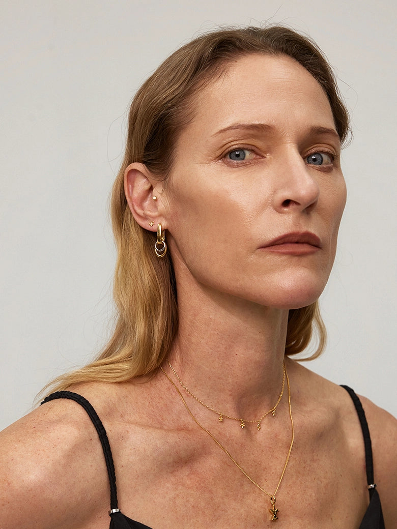 Woman wearing Duo Link Hoop Earrings and layered gold necklaces, showcasing versatile jewelry style.