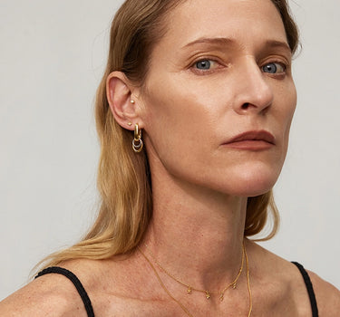 Woman wearing Duo Link Hoop Earrings and layered gold necklaces, showcasing versatile jewelry style.