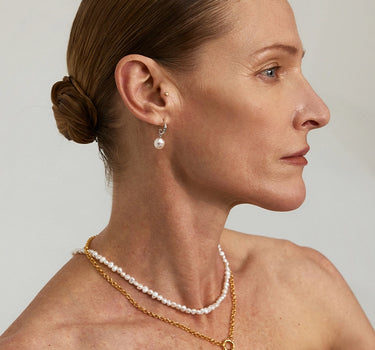 Close-up of a woman's ear showcasing HammeredDiamondDropPearlEarrings