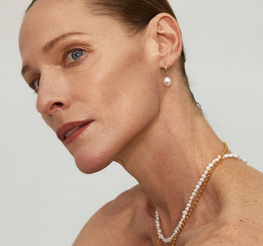 Close-up of a woman's ear showcasing HammeredDiamondDropPearlEarrings