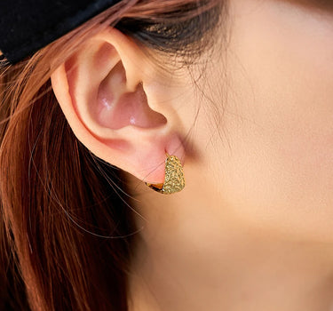 Close-up of a woman's ear showcasing HammeredHoopEarrings