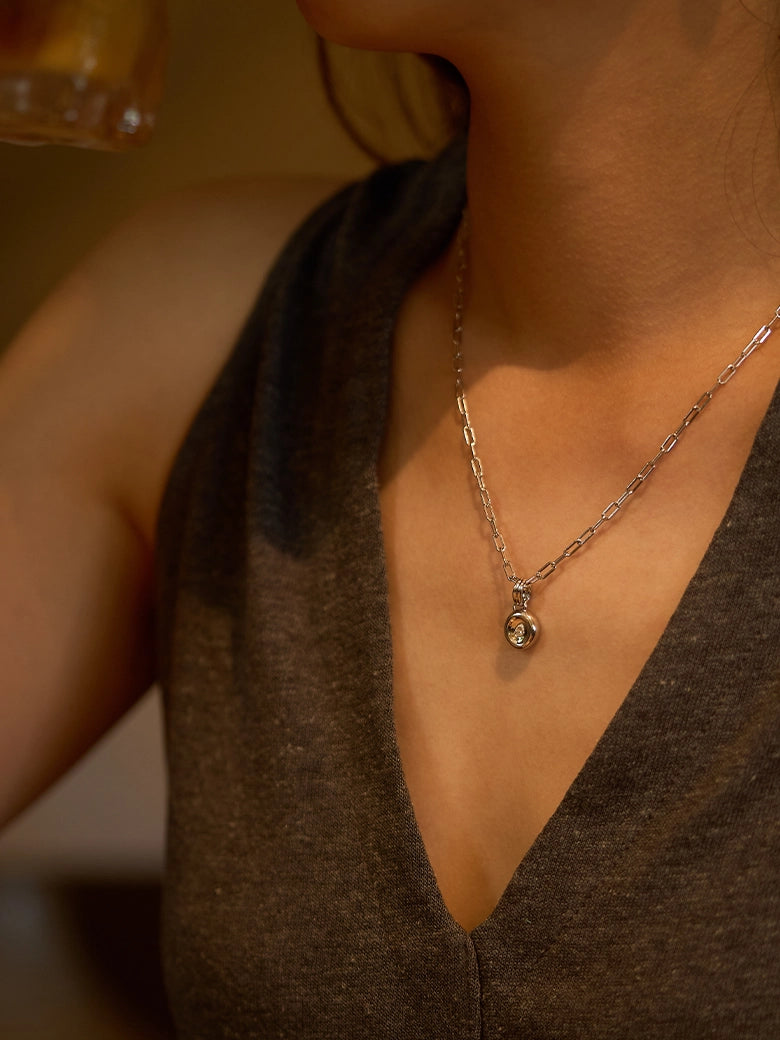 A woman wearing a Pear Dome Silver Pendant Necklace with a moissanite stone on a paperclip chain.