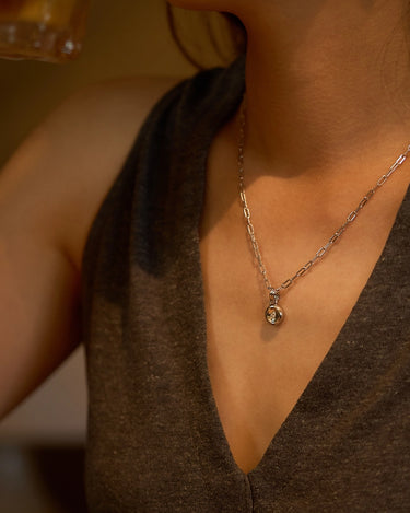 A woman wearing a Pear Dome Silver Pendant Necklace with a moissanite stone on a paperclip chain.