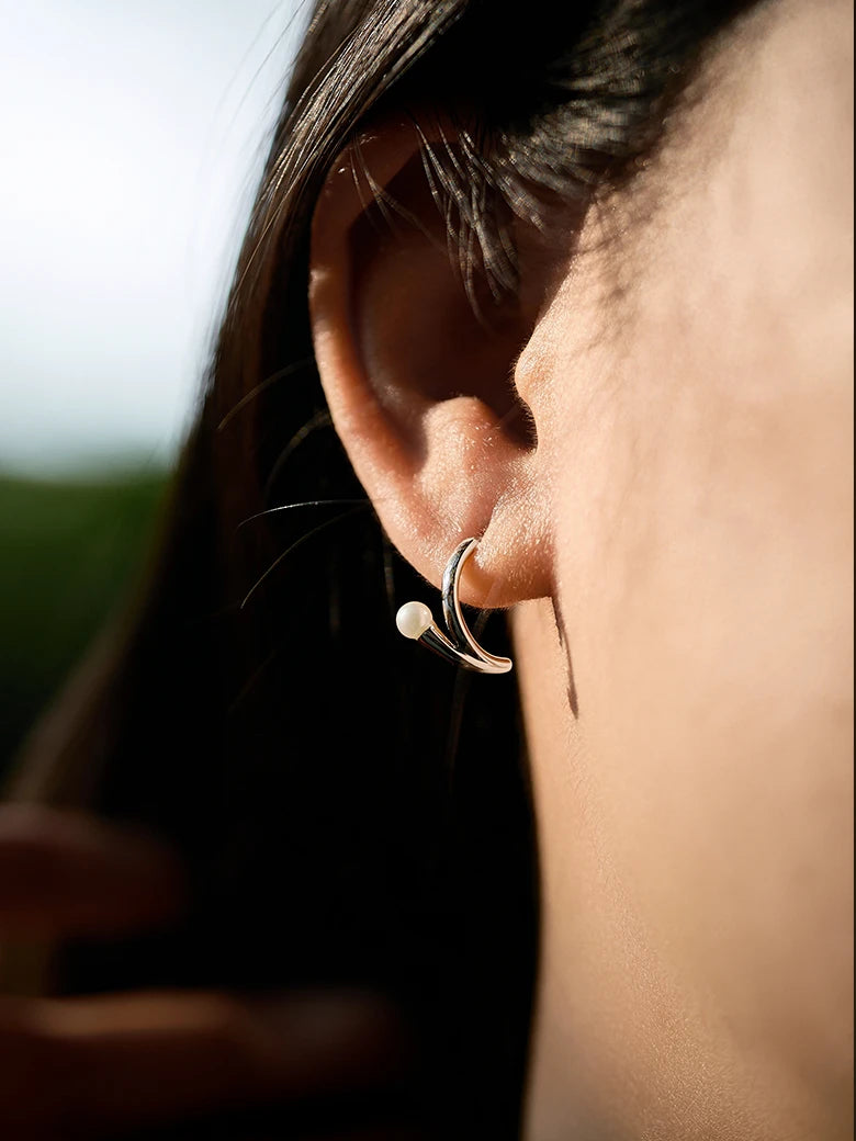 Close-up of a woman's ear showcasing PearlSilverArcEarrings