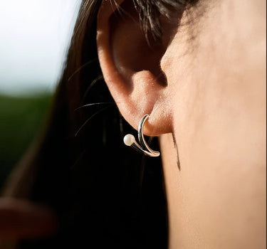Close-up of a woman's ear showcasing PearlSilverArcEarrings