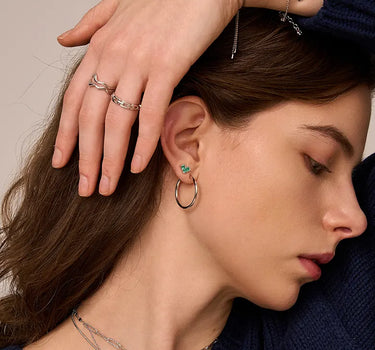 Close-up of a woman's ear showcasing PrincessCutEmeraldHeartSilverHoopEarrings