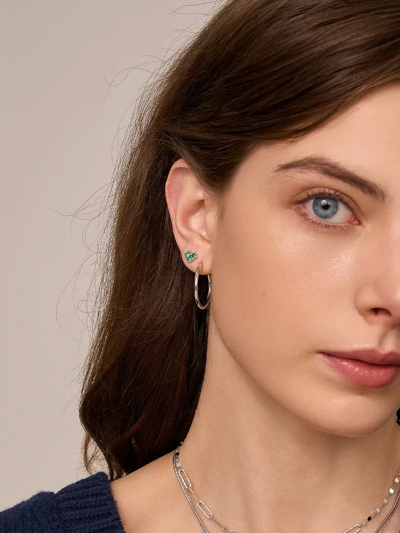 Close-up of a woman's ear showcasing PrincessCutEmeraldHeartSilverHoopEarrings