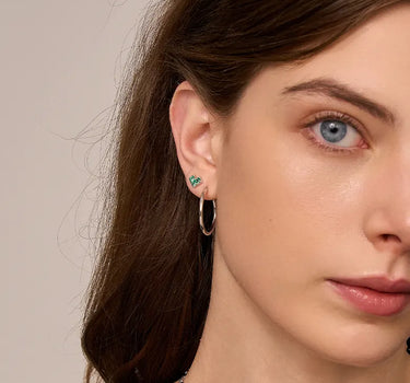 Close-up of a woman's ear showcasing PrincessCutEmeraldHeartSilverHoopEarrings