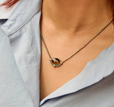 Close-up of a woman's neck showcasing Tiger Eye Signature Charm NecklaceTigerEyeSignatureCharmNecklace