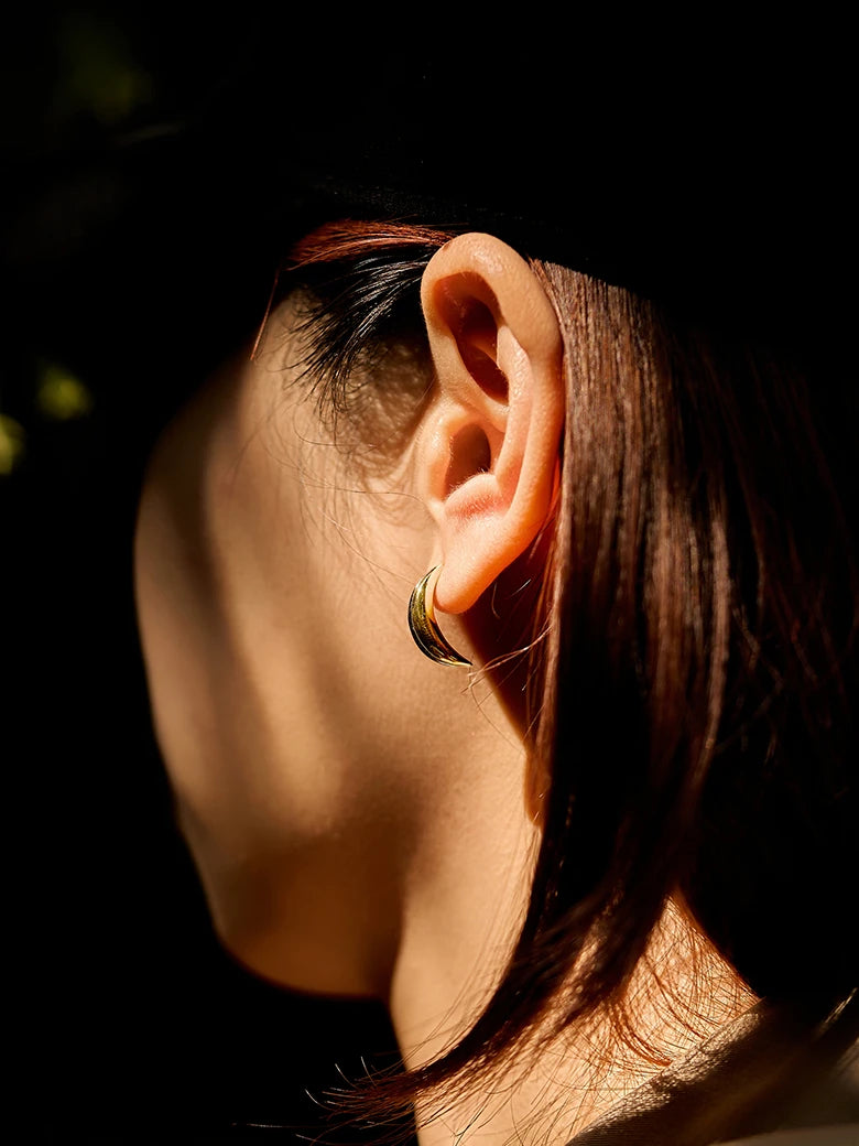 Close-up of a woman's ear showcasing Moon Wavy Silver Stud Earrings